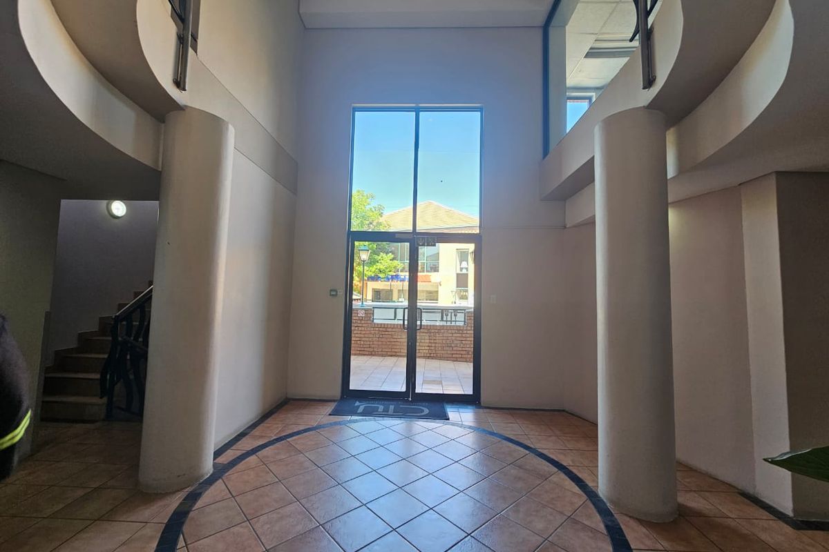 Spacious double-volume entrance foyer featuring tiled flooring, structural columns, and a grand staircase leading to the upper level.