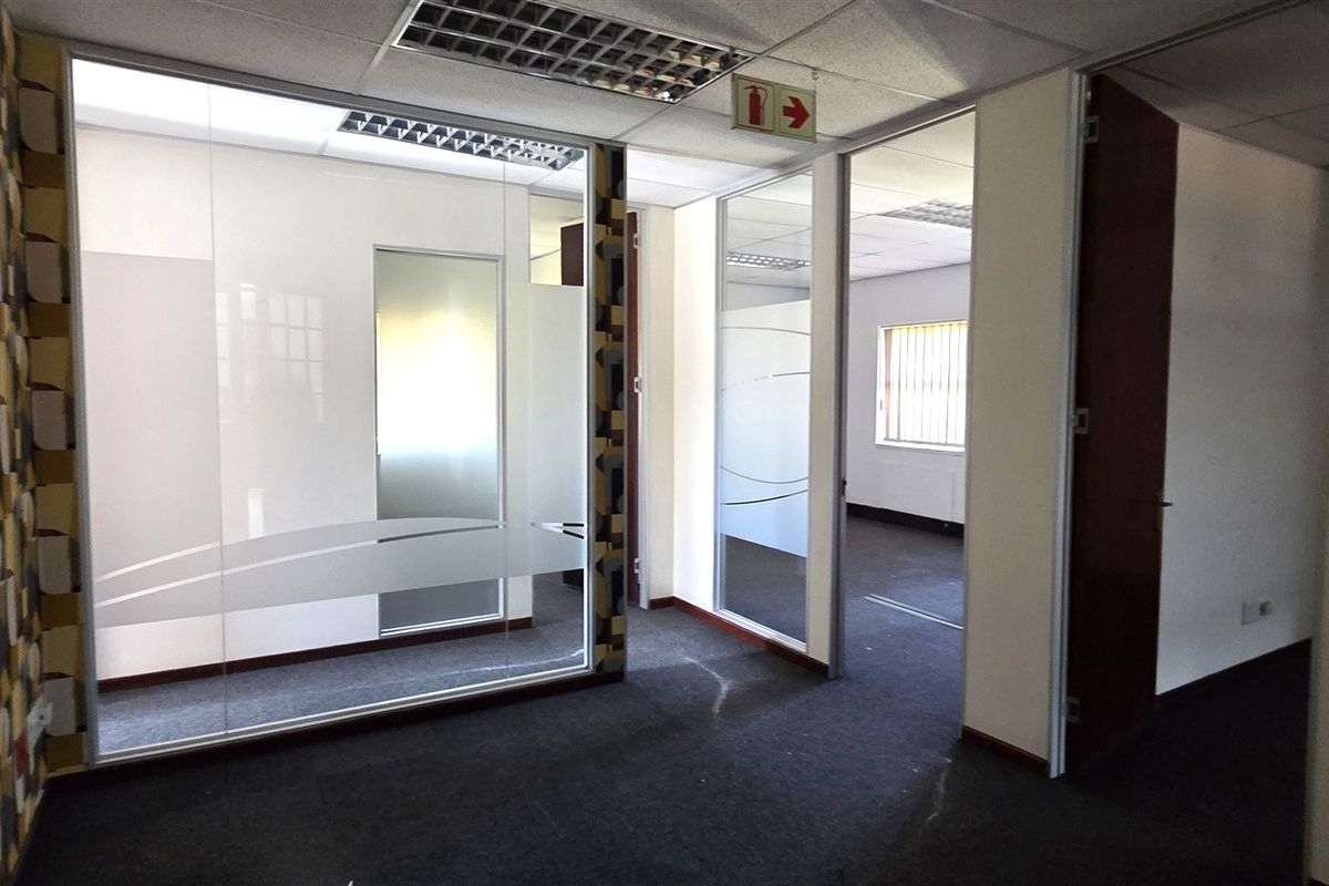 Professional office space featuring glass partitioning, suspended ceilings with recessed lighting, and carpeted flooring, offering a clean and functional layout for business operations.