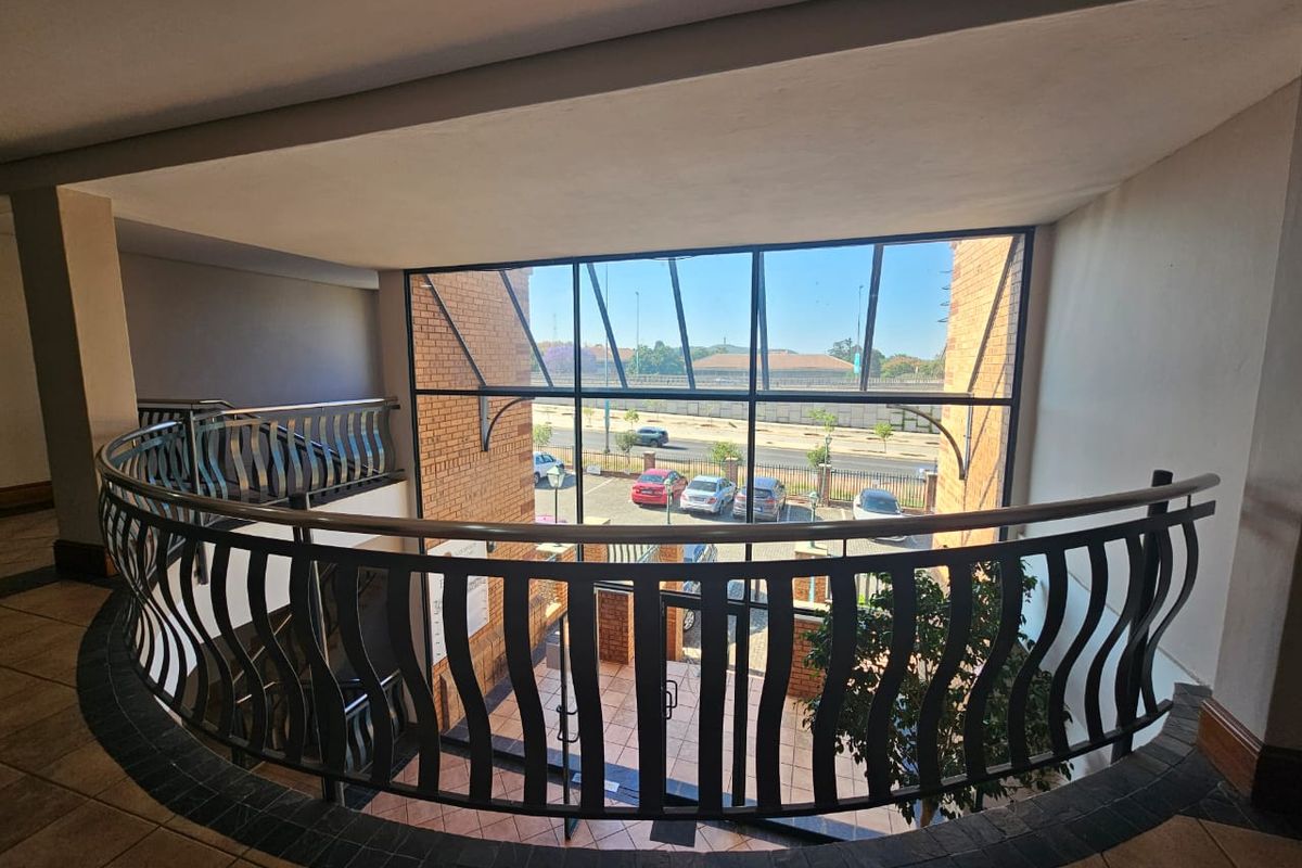 A bright, open-plan landing area featuring a curved metal balustrade and expansive glass windows overlooking the exterior parking area.