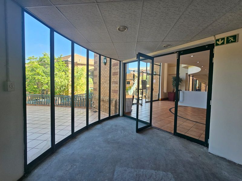 A bright, glass-enclosed entrance area featuring floor-to-ceiling windows, recessed lighting, and direct access to an outdoor patio space.