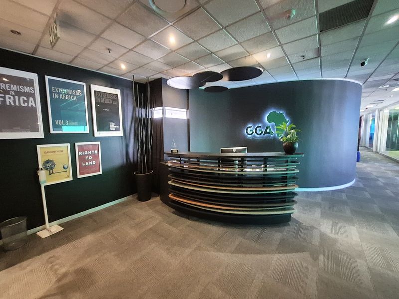 Professional office reception area featuring a curved desk, modern feature wall, and integrated lighting within a suspended ceiling system.