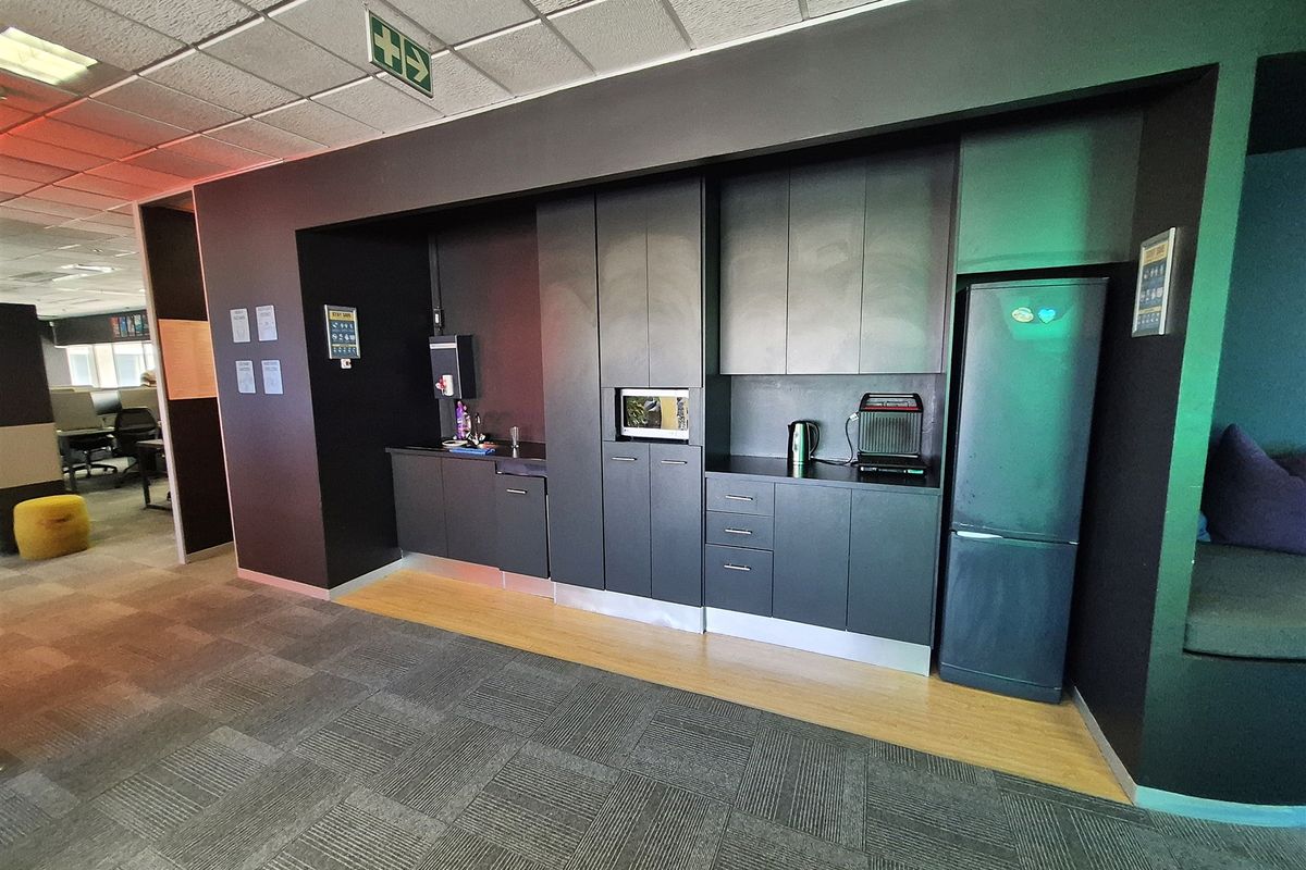 A modern office kitchenette featuring dark built-in cabinetry, integrated microwave, and a clean, functional layout for staff use.