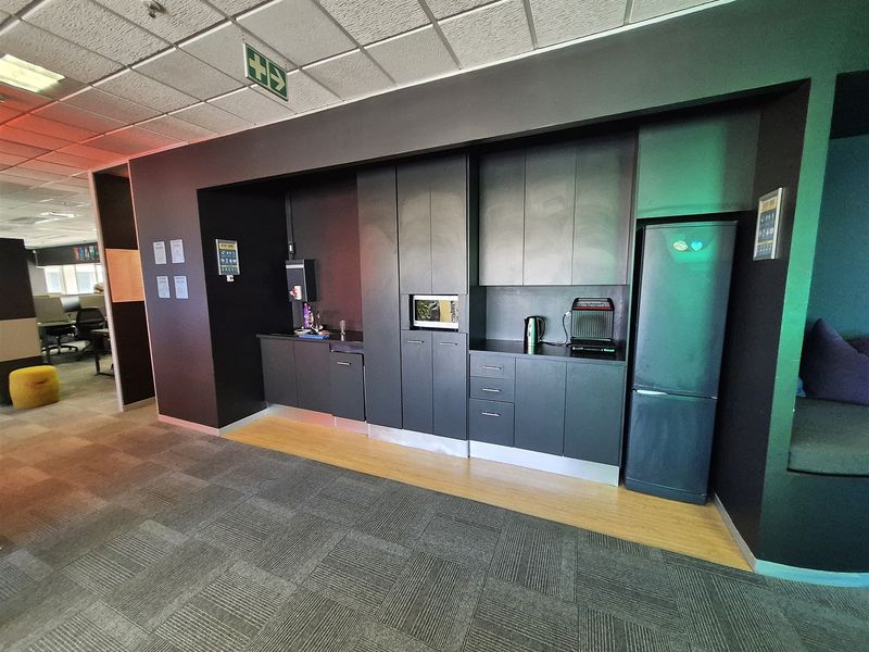 A modern office kitchenette featuring dark built-in cabinetry, integrated microwave, and a clean, functional layout for staff use.