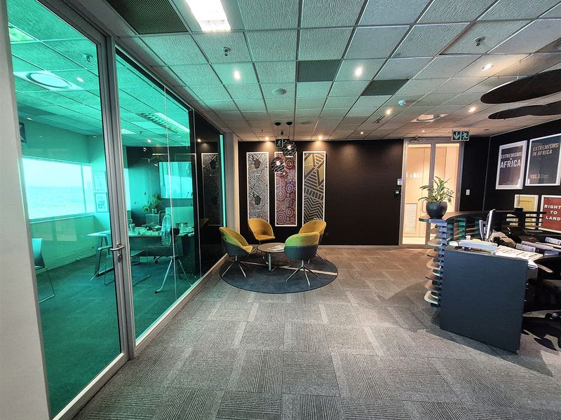 Modern office space featuring a reception area, glass-partitioned meeting room, suspended ceiling with recessed lighting, and professional carpet tile flooring.