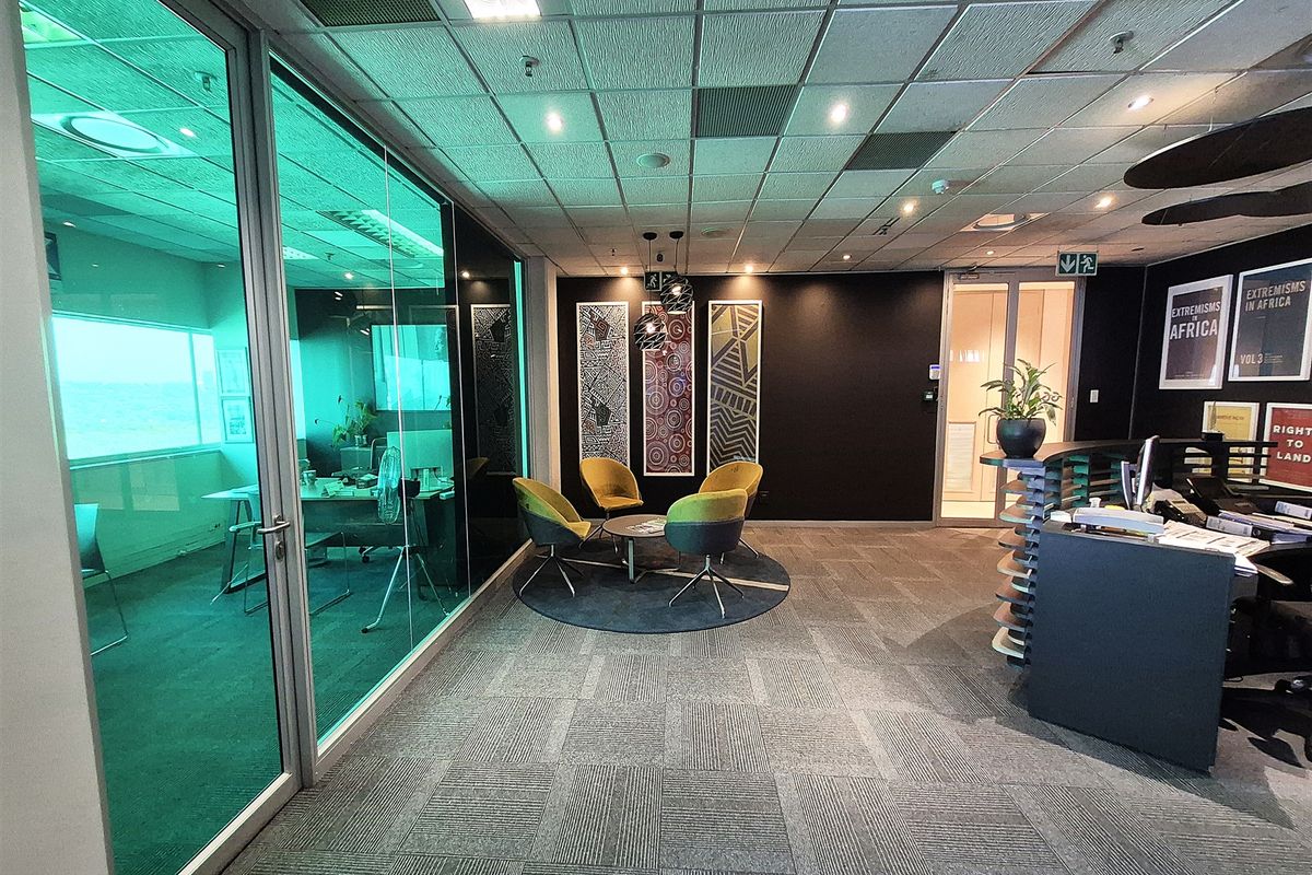 Modern office space featuring a reception area, glass-partitioned meeting room, suspended ceiling with recessed lighting, and professional carpet tile flooring.