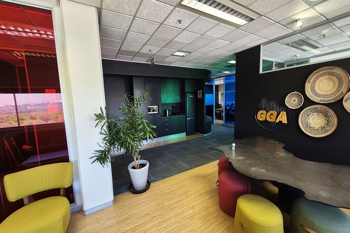 Modern office space featuring a combination of laminate and carpet flooring, a built-in kitchenette, and a contemporary open-plan layout with glass partitions.