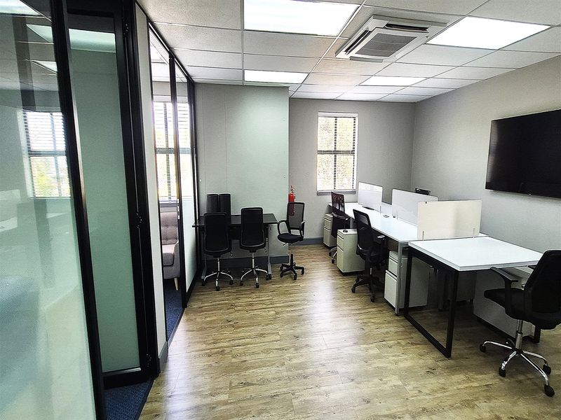 A modern, well-lit office space featuring glass partitions, wood-look flooring, and integrated ceiling air conditioning, providing a professional and functional work environment.