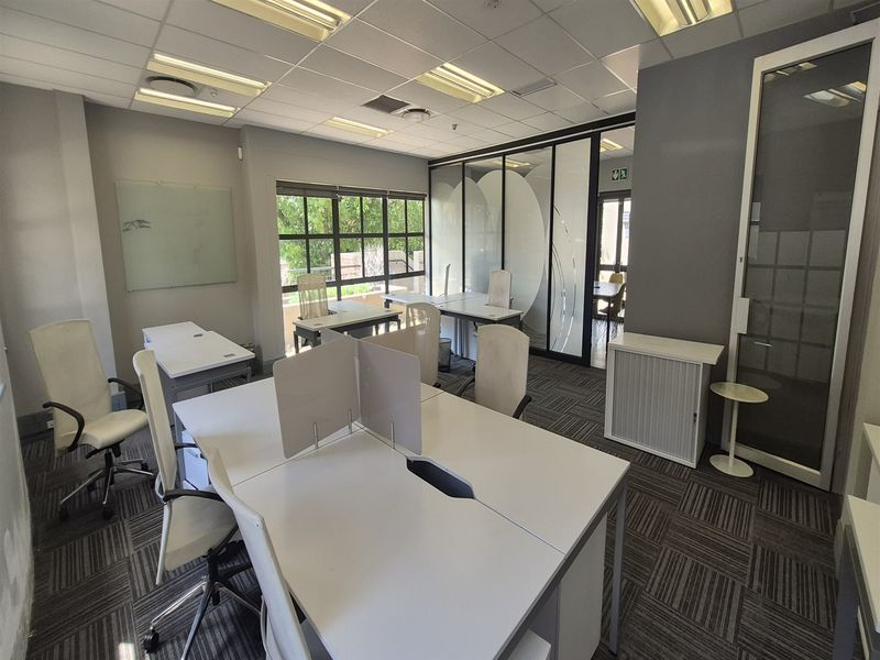 A professional office space featuring carpeted flooring, suspended ceilings with recessed lighting, and glass partition walls for a modern, open-plan work environment.