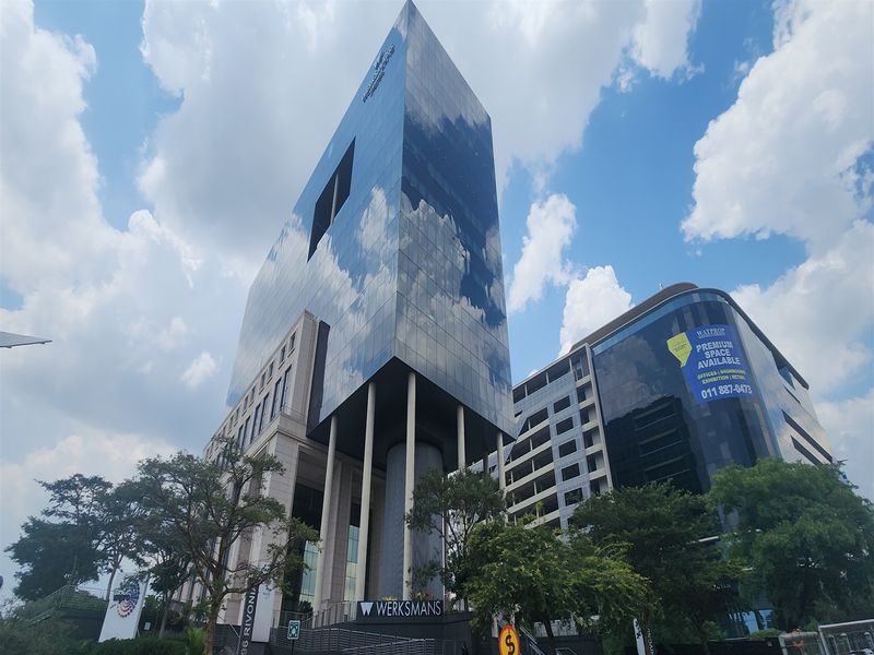Modern high-rise office building featuring a prominent glass facade and architectural structural columns, located in a prime commercial area.