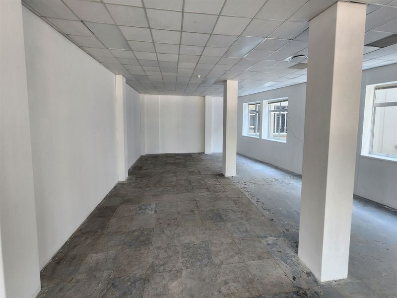 An empty, open-plan office space featuring structural columns, suspended ceiling tiles, and worn flooring, offering a blank canvas for custom fit-out.