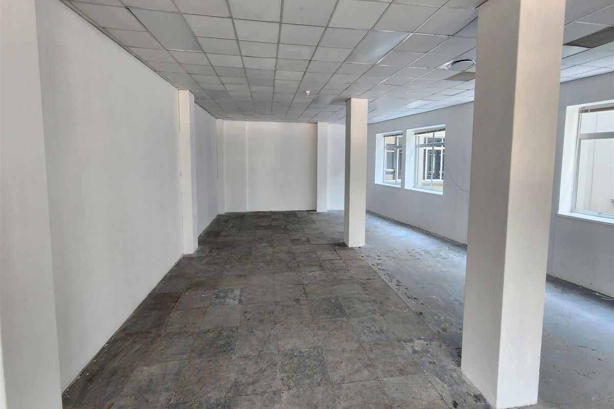An empty, open-plan office space featuring structural columns, suspended ceiling tiles, and worn flooring, offering a blank canvas for custom fit-out.