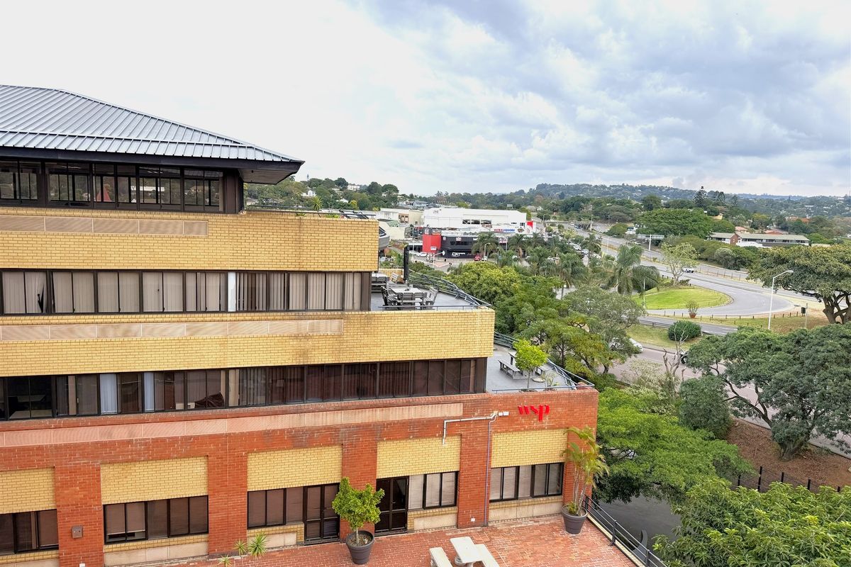 Aerial view of a multi-story office building featuring brick exterior, metal roofing, and a paved terrace area overlooking the surrounding neighborhood.