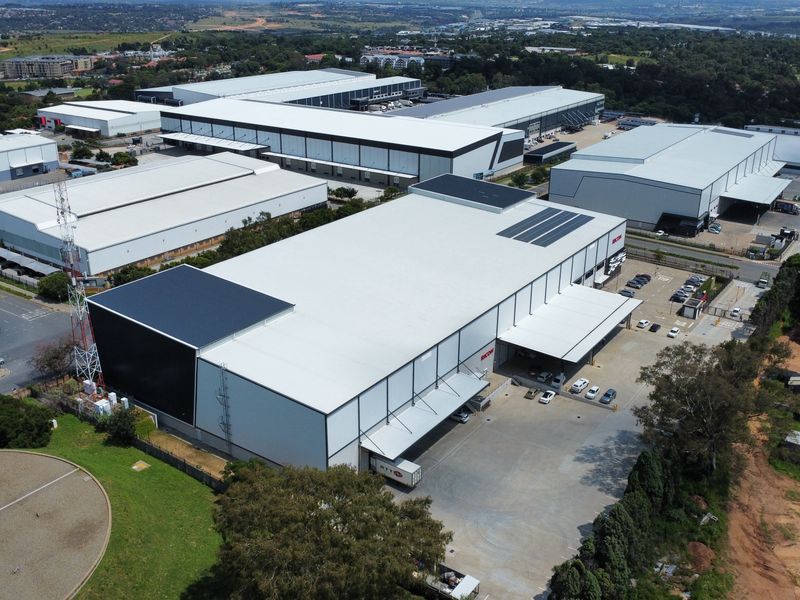 Aerial view of a modern industrial warehouse complex featuring large loading bays, extensive asphalt yard space, and well-maintained metal roofing structures.