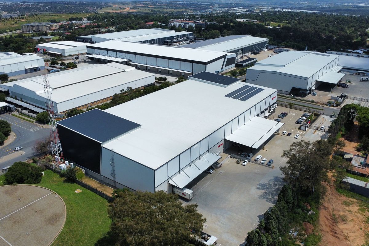 Aerial view of a modern industrial warehouse complex featuring large loading bays, extensive asphalt yard space, and well-maintained metal roofing structures.