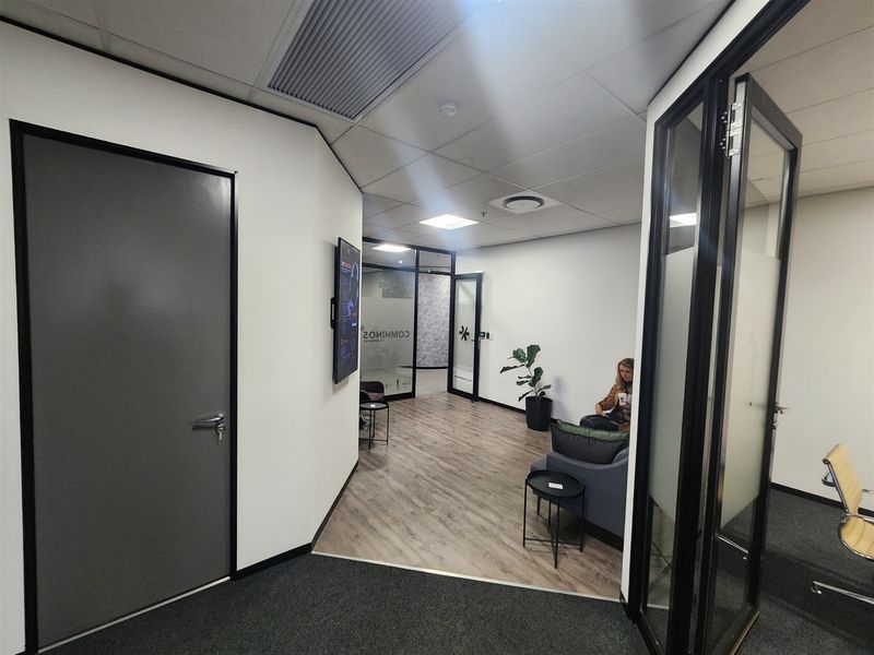 Modern office reception area featuring glass partitions, a mix of carpet and laminate flooring, and integrated ceiling lighting with air conditioning.