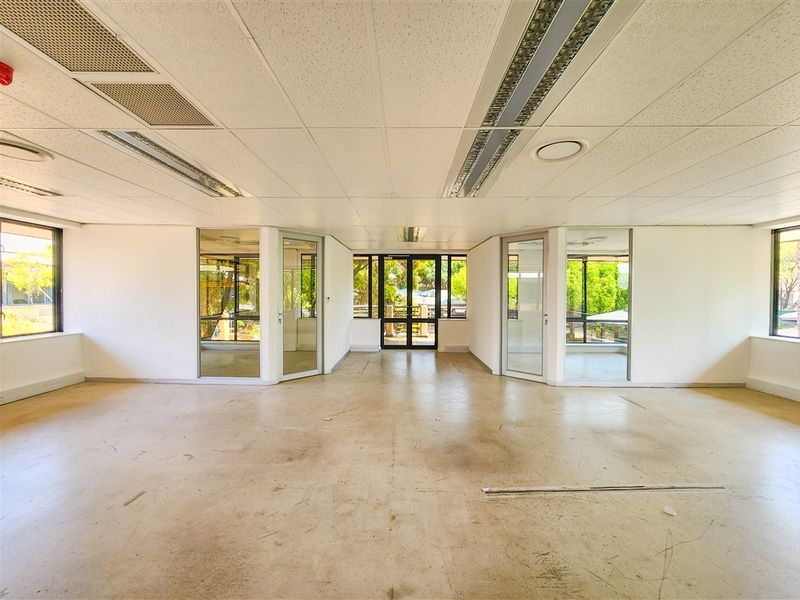An open-plan office space featuring suspended ceilings, recessed lighting, and extensive glass partitioning, offering a bright and flexible layout for professional use.