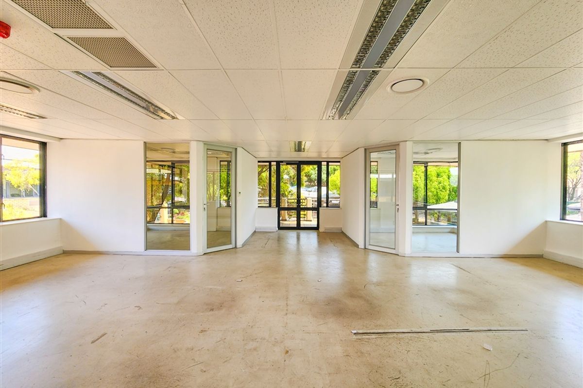 An open-plan office space featuring suspended ceilings, recessed lighting, and extensive glass partitioning, offering a bright and flexible layout for professional use.