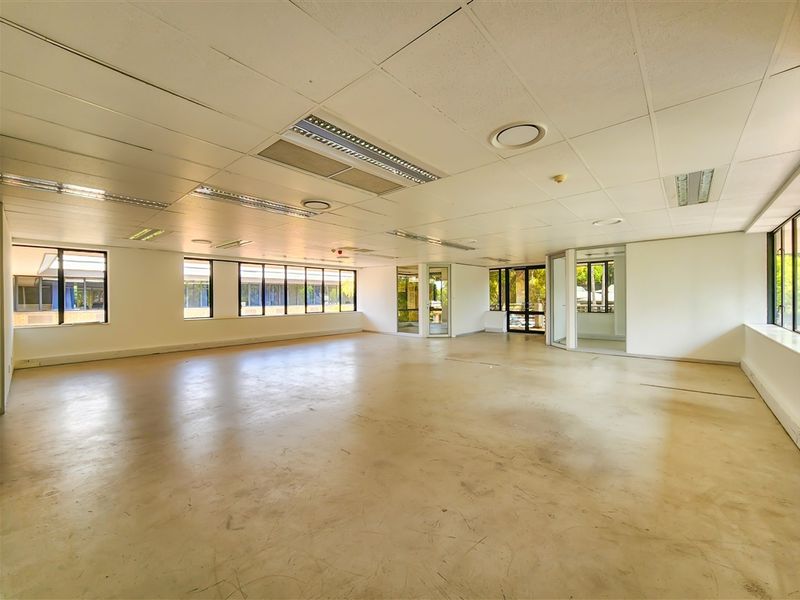 A spacious, open-plan office area featuring large windows, suspended ceilings with recessed lighting, and glass partitions, offering a versatile workspace ready for custom fit-out.