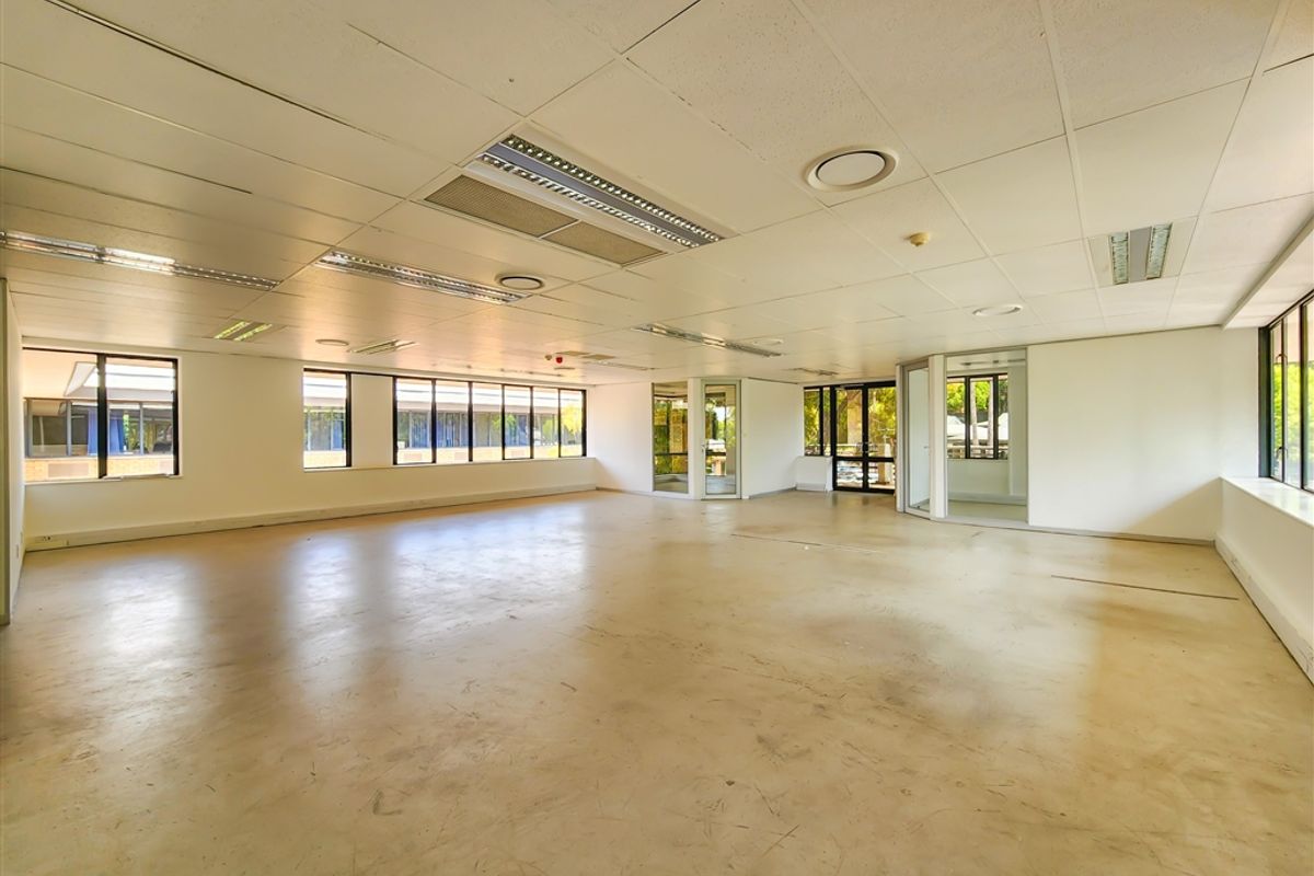 A spacious, open-plan office area featuring large windows, suspended ceilings with recessed lighting, and glass partitions, offering a versatile workspace ready for custom fit-out.