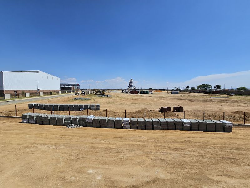 Expansive industrial development site featuring cleared land, perimeter fencing, and construction materials, offering significant potential for future industrial infrastructure projects.