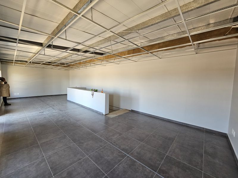 An open-plan industrial space featuring large format floor tiles and an unfinished exposed ceiling grid, offering a blank canvas for custom fit-out.