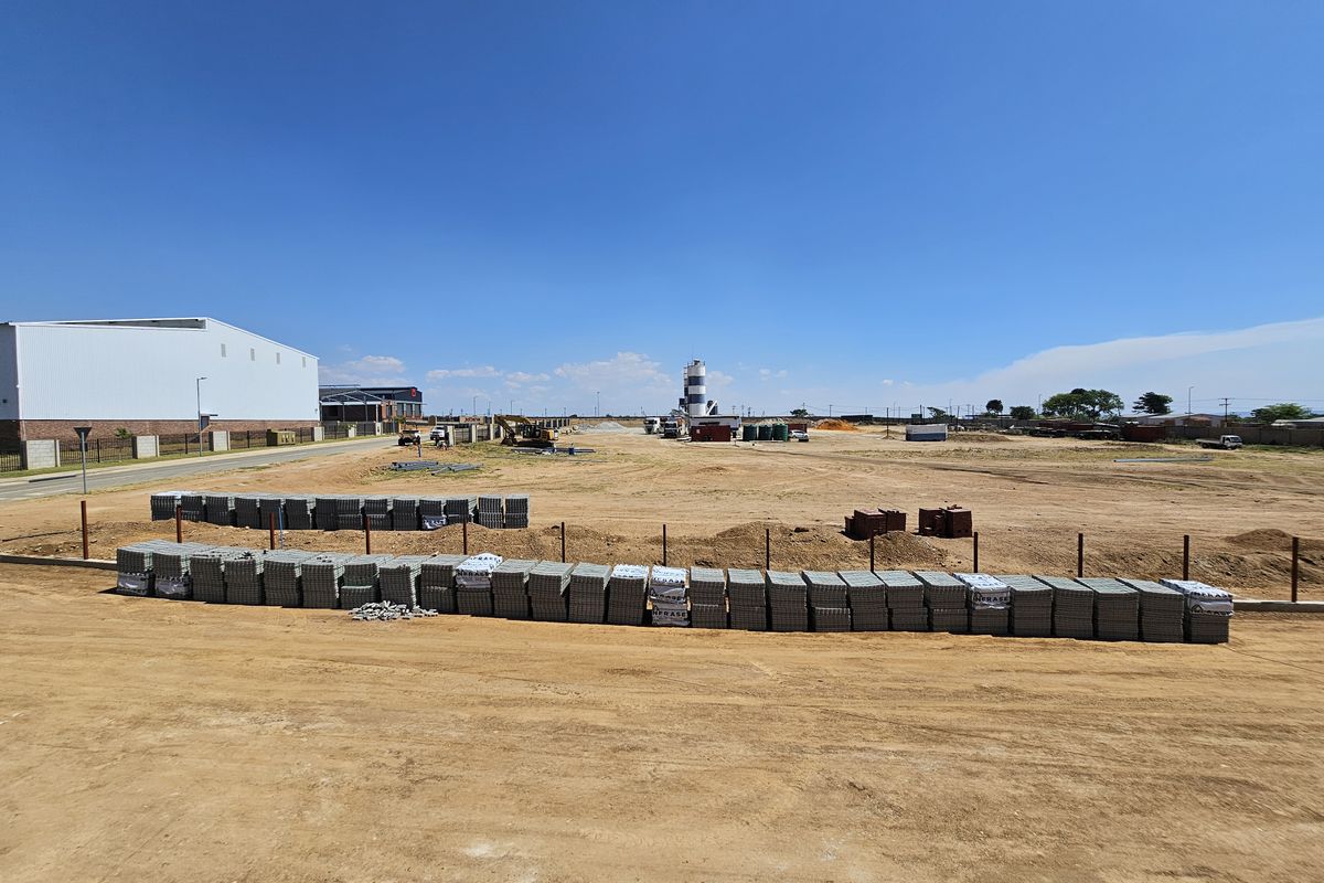 Expansive industrial development site featuring cleared land, perimeter fencing, and construction materials, offering significant potential for future industrial infrastructure projects.