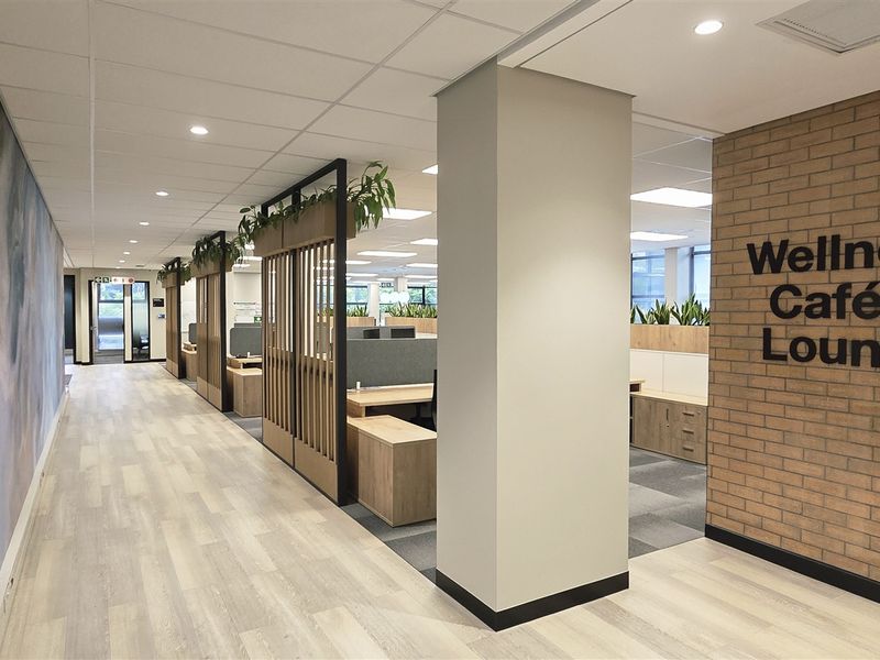 Modern office interior featuring a wellness cafe and lounge area with contemporary finishes, exposed brick accents, and professional open-plan workspace layout.