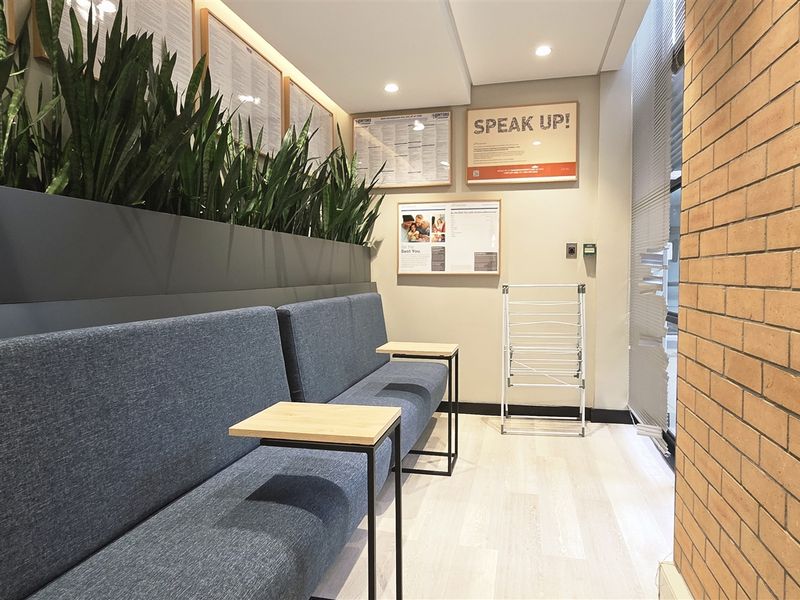 A modern office waiting area featuring an exposed brick wall, recessed lighting, and a built-in planter box with integrated seating.