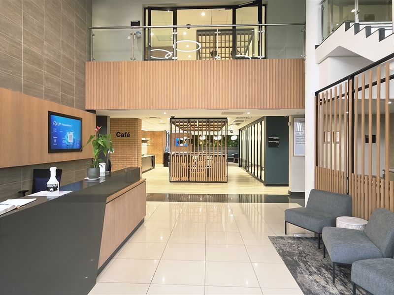 Modern office reception area featuring a sleek reception desk, tiled flooring, and a feature staircase with timber slat detailing and glass balustrades.