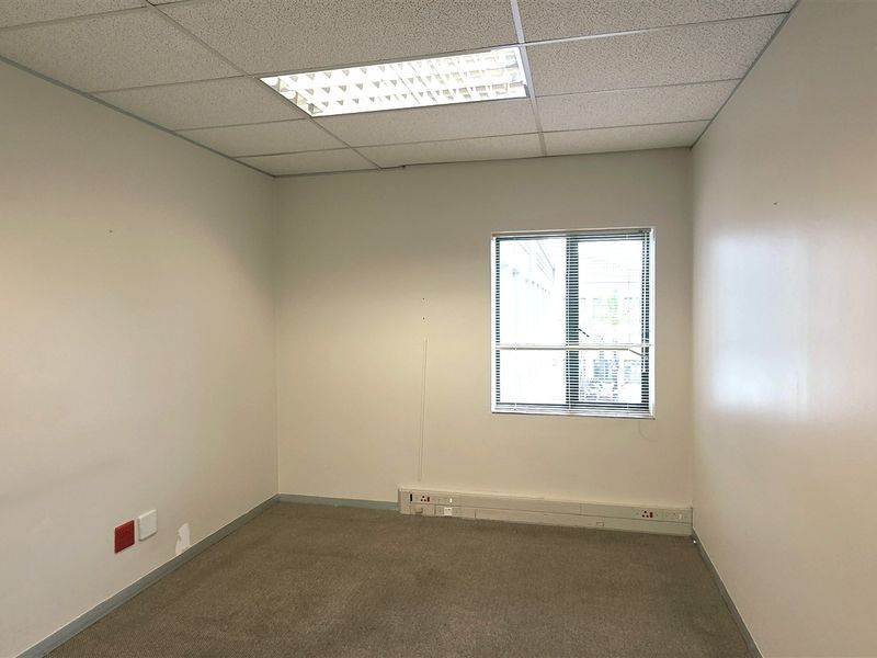 A vacant office space featuring a suspended ceiling, recessed lighting, carpeted flooring, and perimeter trunking for electrical connectivity.