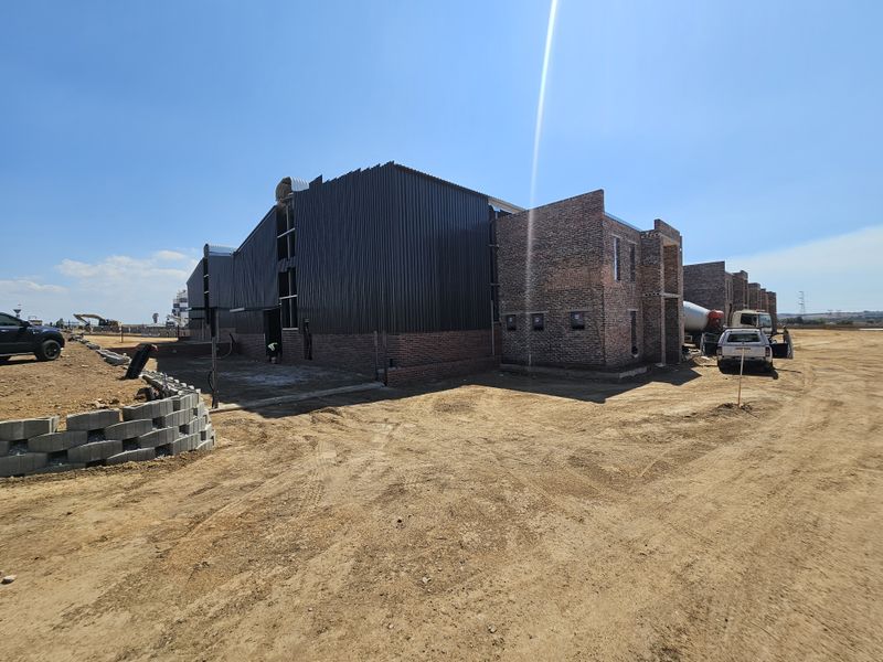Rear view of an industrial property under construction, featuring a combination of face brick and corrugated metal cladding on a large site.