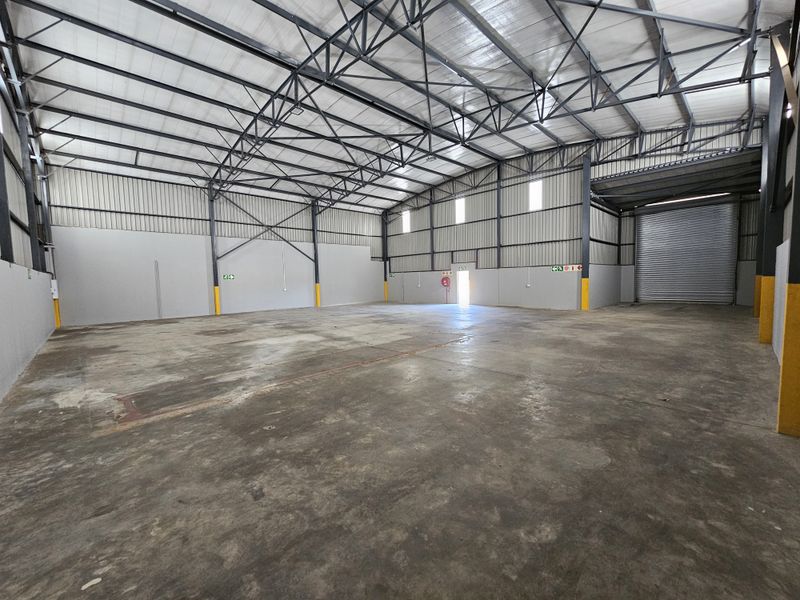 Spacious industrial warehouse unit featuring high ceilings, steel portal frame construction, concrete flooring, and a large roller shutter door for easy access.