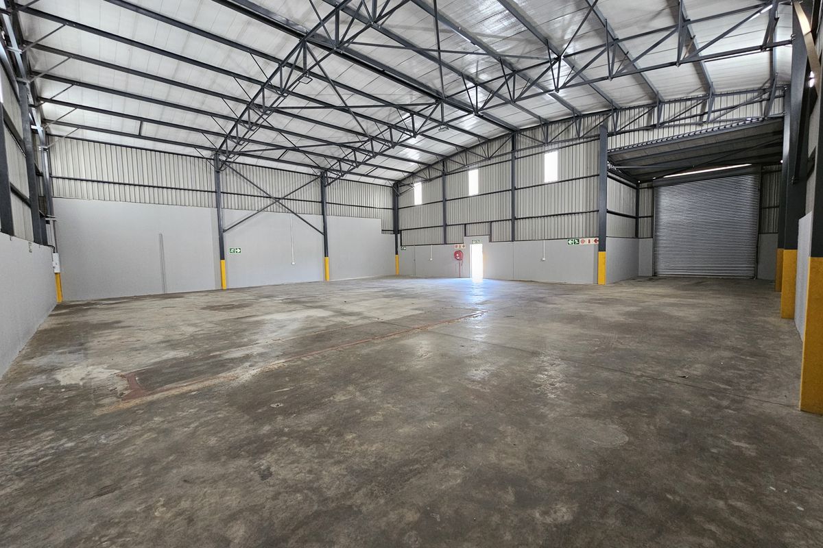 Spacious industrial warehouse unit featuring high ceilings, steel portal frame construction, concrete flooring, and a large roller shutter door for easy access.