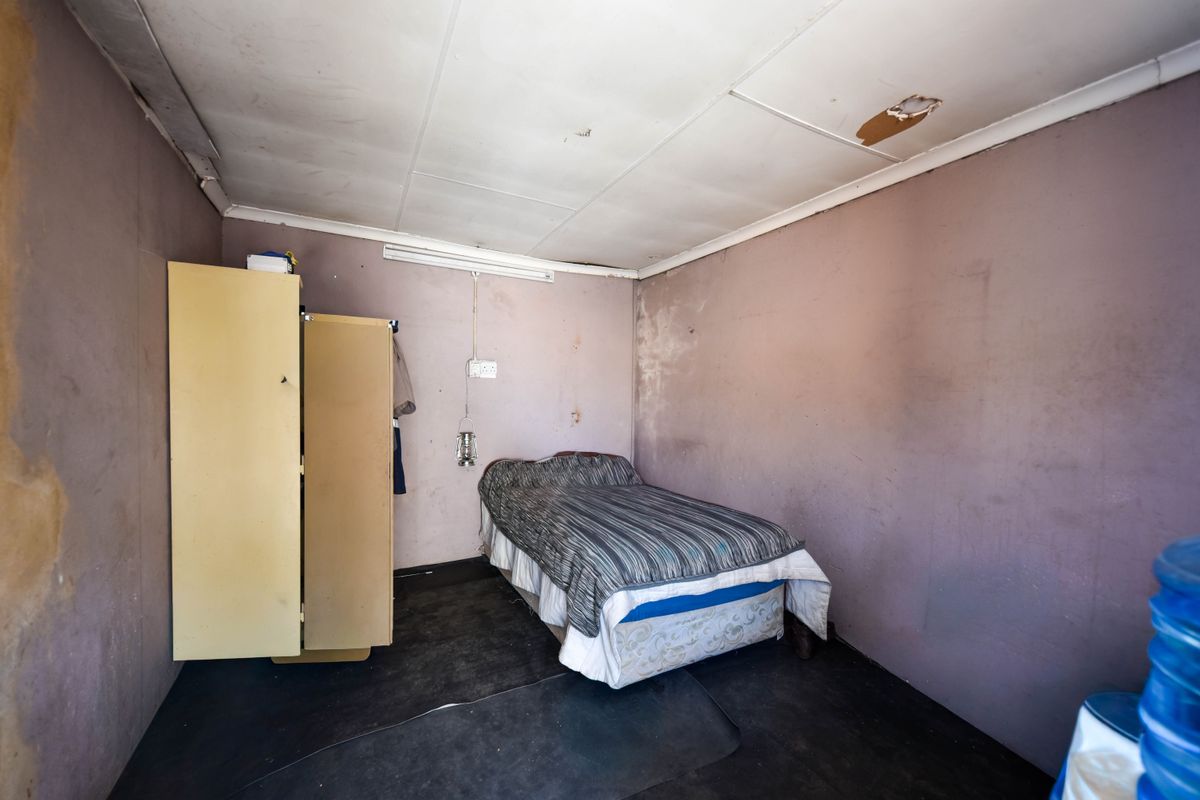 A bedroom space featuring basic finishes, requiring significant maintenance and cosmetic updates to improve the overall condition and appeal of the room.