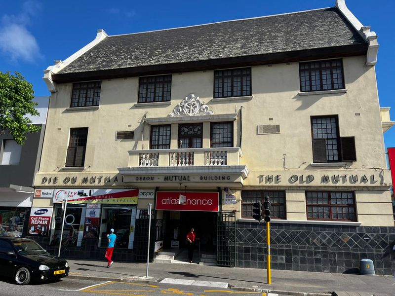 Historic commercial building facade featuring traditional architectural details, ground-floor retail storefronts, and a prominent central entrance.