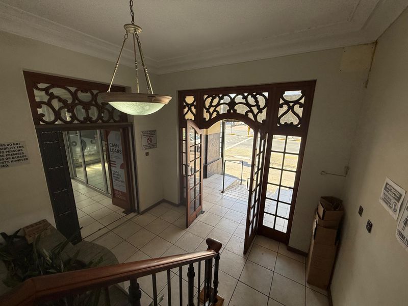 Commercial building entrance foyer featuring decorative timber door frames, tiled flooring, and a classic pendant light fixture.