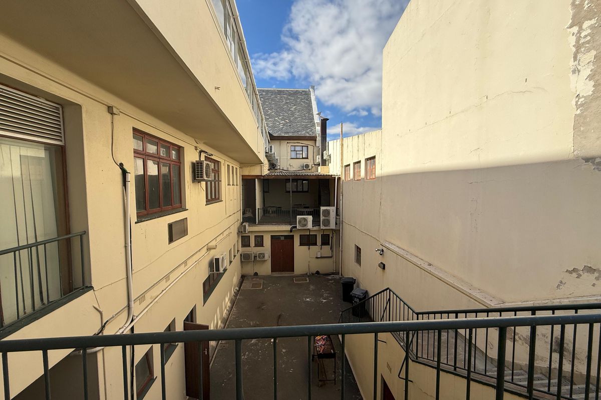 View of the rear courtyard area of the commercial property, featuring paved ground, external staircases, and multiple wall-mounted air conditioning units.