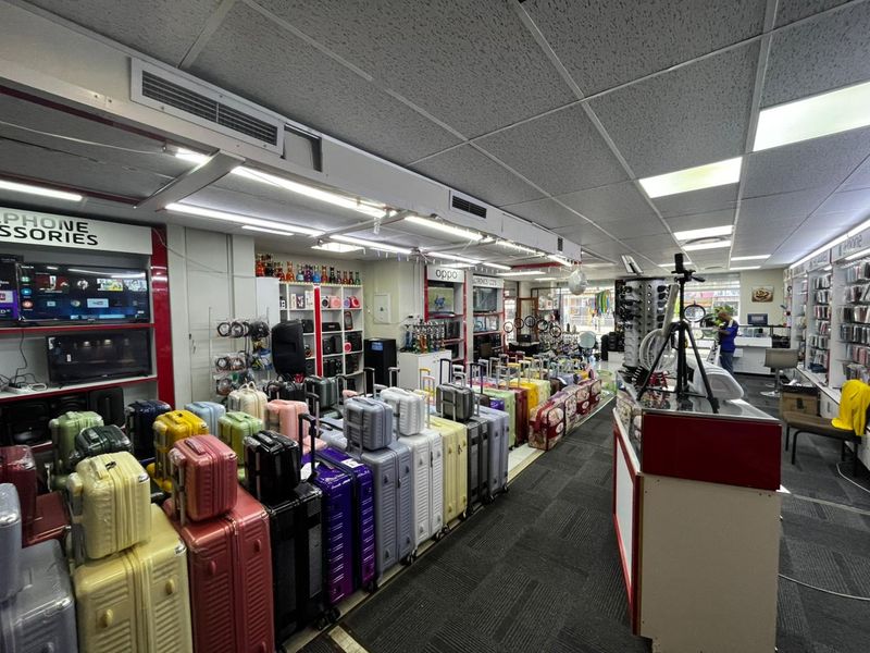 Commercial retail space featuring a drop ceiling with integrated lighting, carpeted flooring, and built-in wall shelving units for product display.
