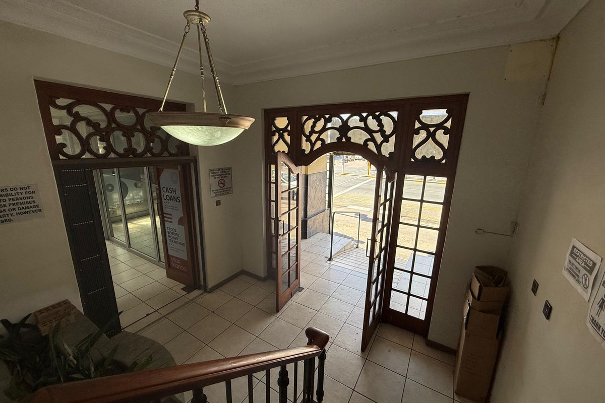 Commercial building entrance foyer featuring decorative timber door frames, tiled flooring, and a classic pendant light fixture.