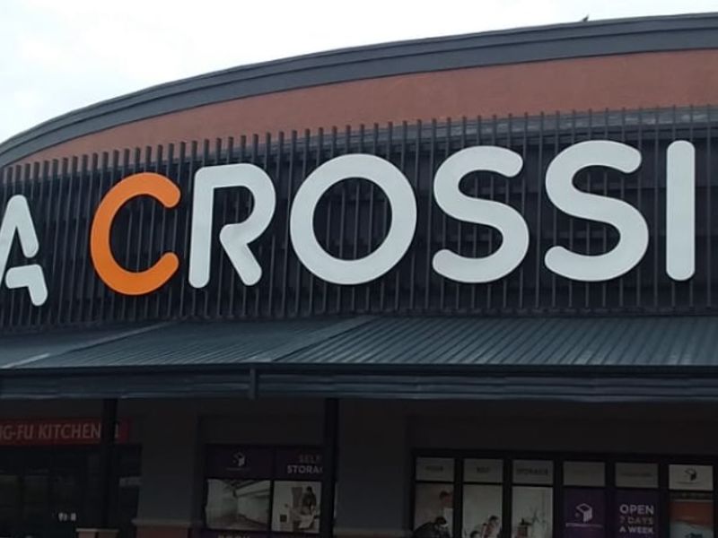 Exterior view of the Montana Crossing retail center, featuring prominent signage, a covered walkway, and modern architectural facade elements.