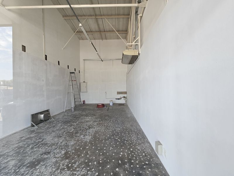 An empty retail space featuring high ceilings, exposed structural elements, and tiled flooring, suitable for a variety of commercial or retail business applications.