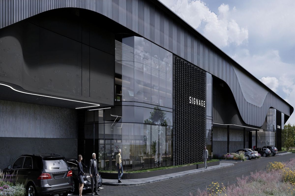 Modern industrial facility featuring a striking architectural facade with extensive glass curtain walling, metal cladding, and a professional paved entrance area.