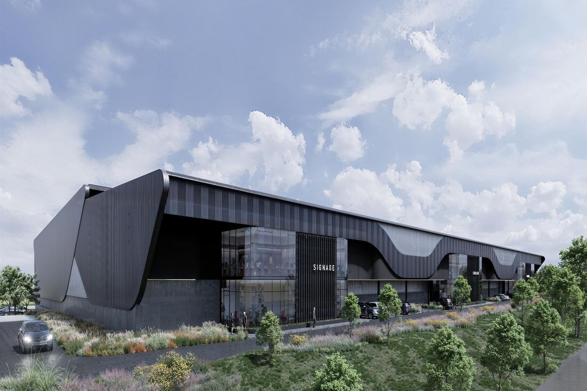 Modern industrial warehouse facility featuring sleek black metal cladding, expansive glass facade, and professional landscaping.