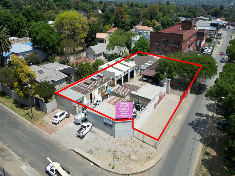 Aerial view of an industrial workshop property featuring multiple bays, secure perimeter fencing, and corner street access in a mixed-use area.