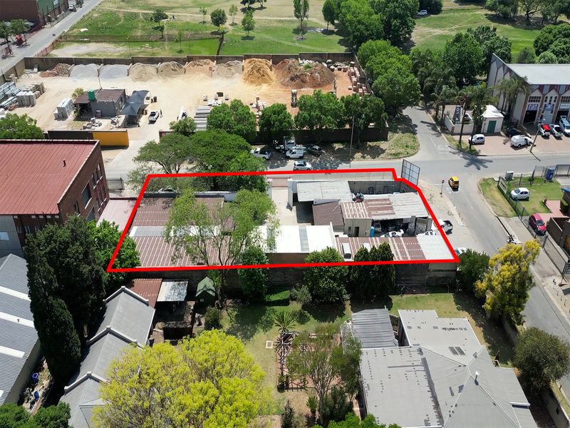 Aerial view of an industrial property featuring multiple connected warehouse structures with metal roofing, situated on a corner lot with perimeter fencing.
