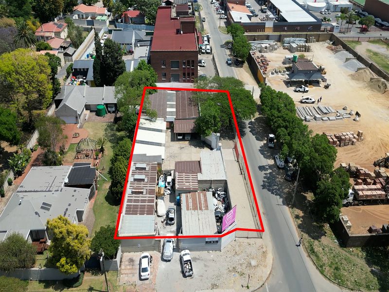 Aerial view of an industrial property featuring multiple warehouse structures with metal roofing, situated on a corner lot with street access.