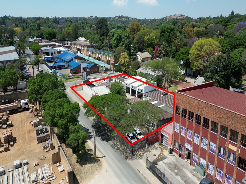 Aerial view of an industrial property featuring a warehouse structure with multiple bays, situated in a mixed-use urban area.