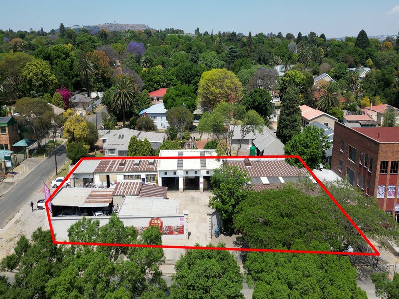 Aerial view of an industrial property featuring multiple workshop bays, corrugated metal roofing, and a paved yard area within a suburban setting.