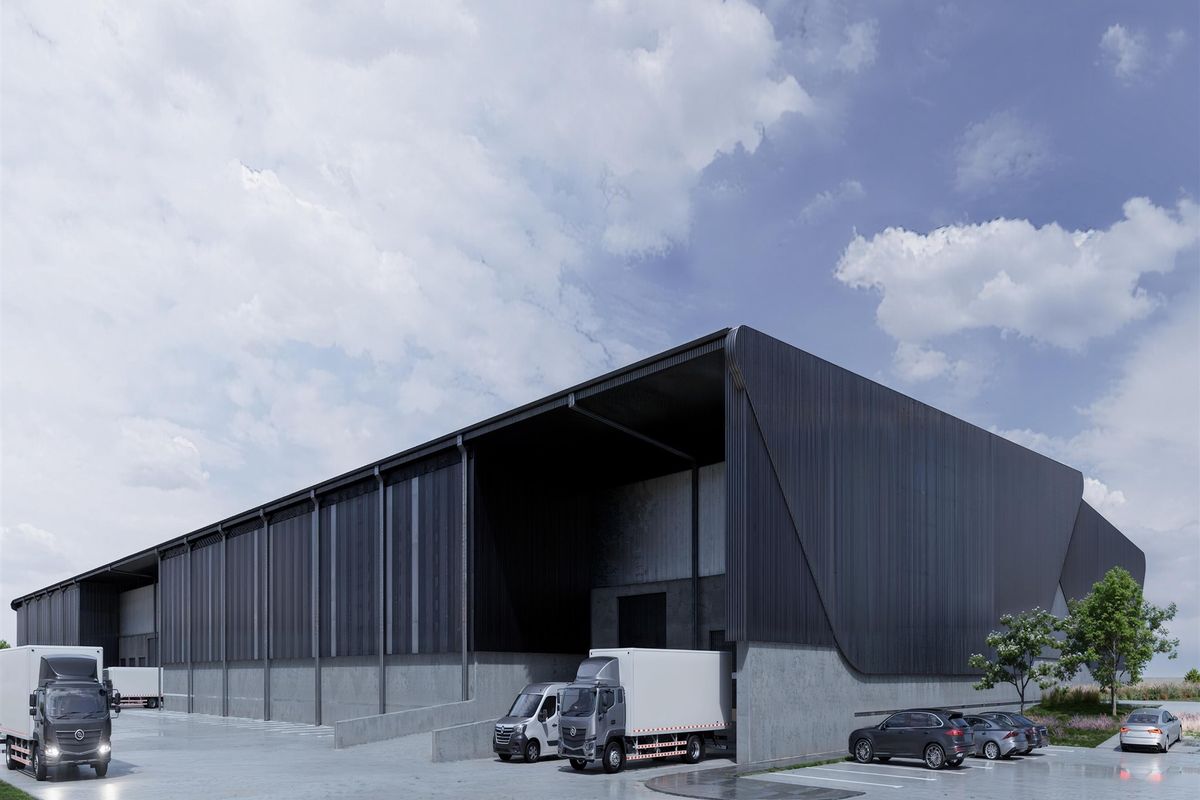 Modern industrial warehouse facility featuring extensive metal cladding, a large covered loading bay, and a spacious concrete hardstand area for logistics operations.