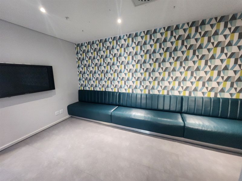 A modern office breakout area featuring built-in bench seating, a geometric patterned feature wall, and recessed ceiling lighting.